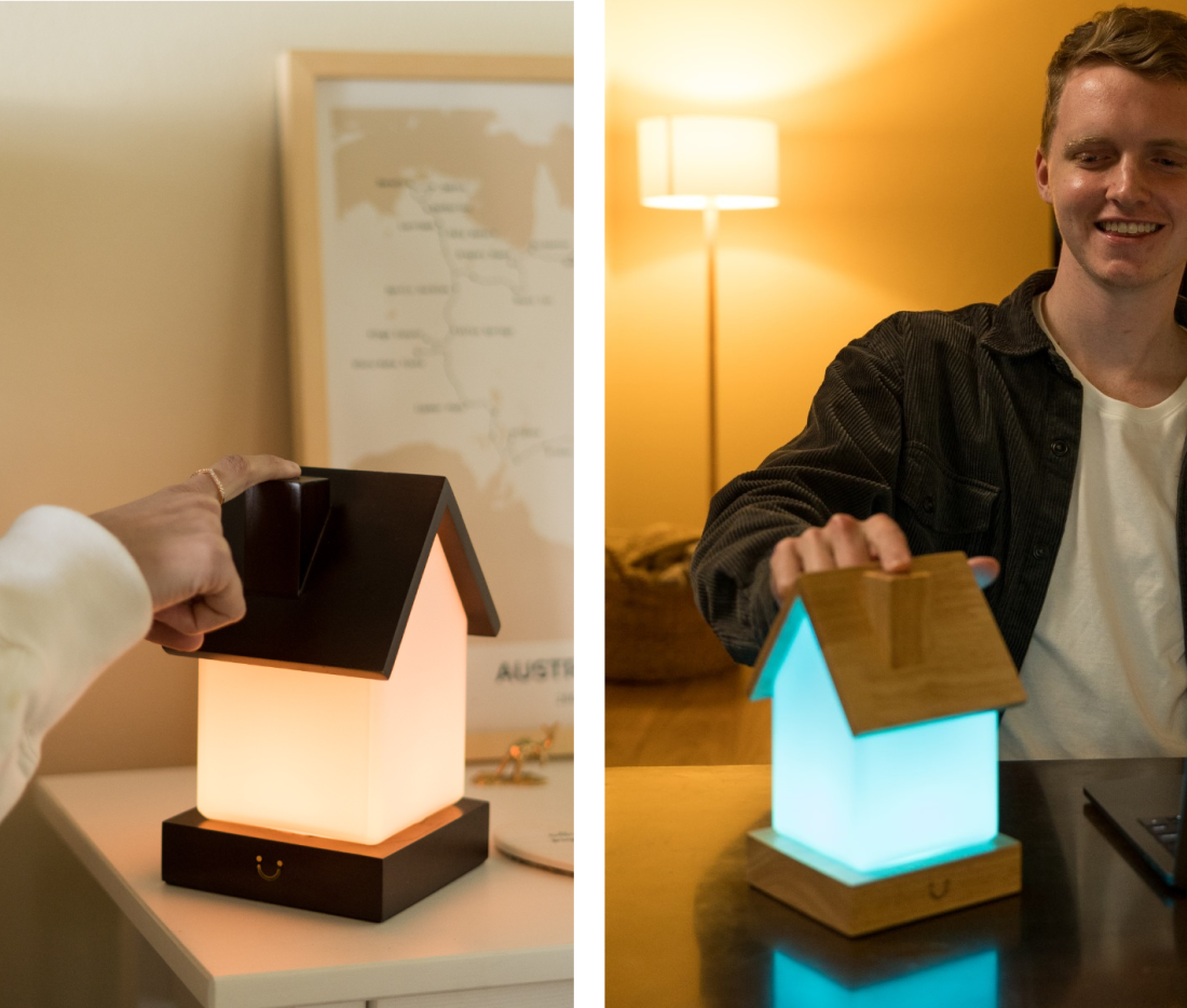 Person opening a wooden friendship lamp to reveal its cyan glow beside another in warm white mode.
