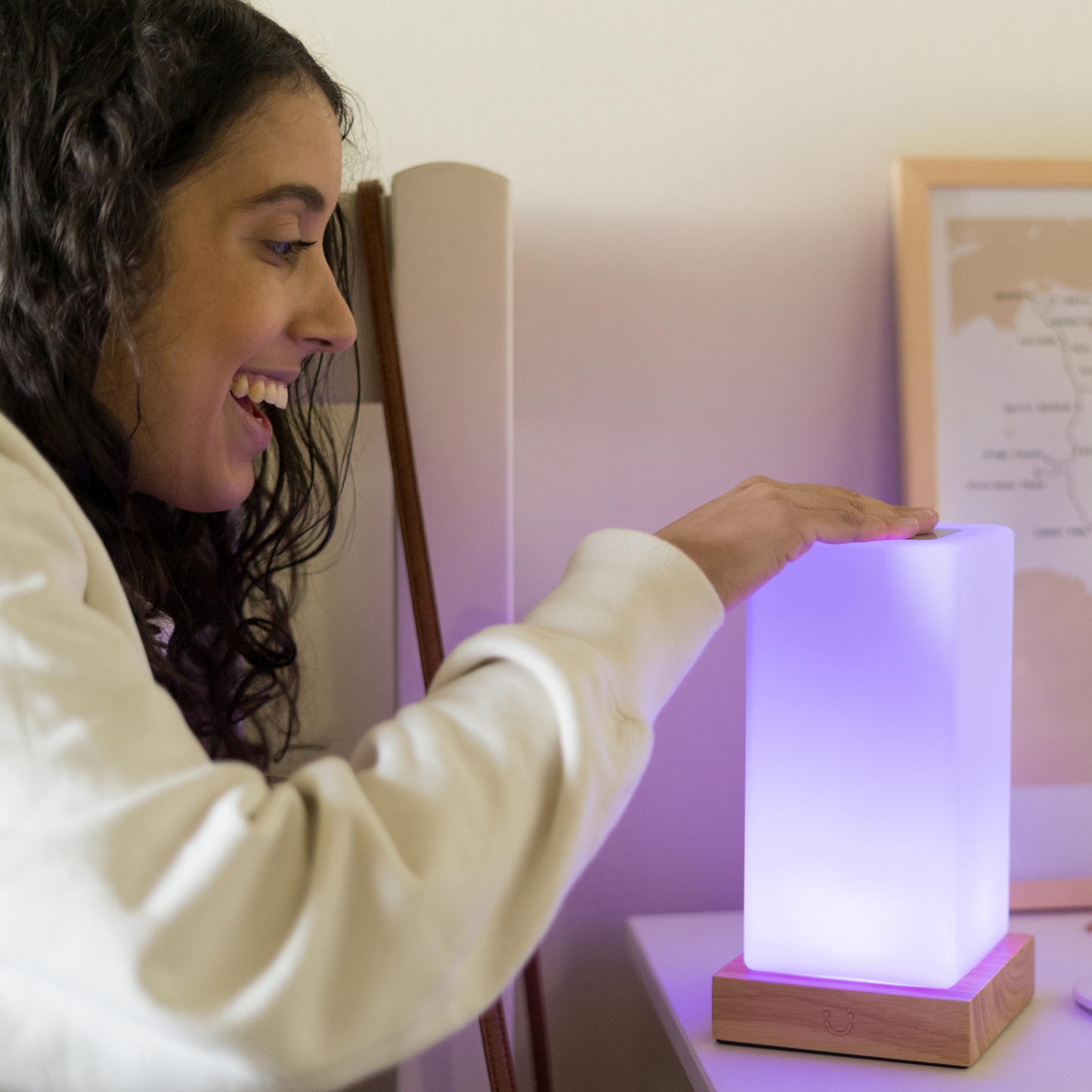 Touching a Modern Tower Lamp that glows vibrant purple from a wooden base.