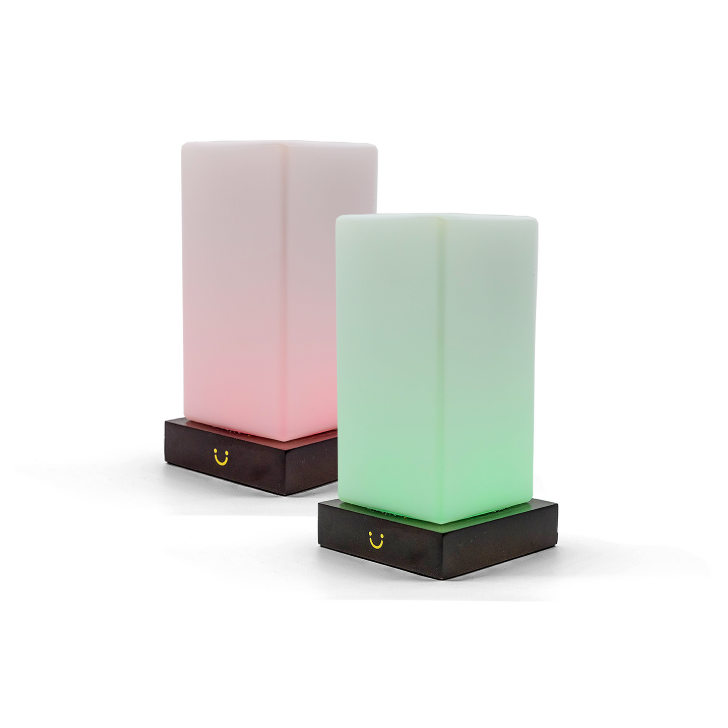 Pair of friendship lamps illuminated in soft pink and green with dark wooden bases.